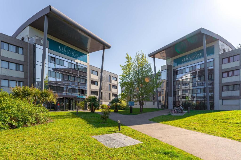 a large building with a grassy area in front of it at Zenitude Hôtel-Résidences Nantes Métropole in Nantes