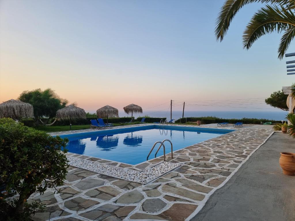einen Pool in einem Resort mit einer Palme in der Unterkunft Bellevue Village ''Αdults Only'' in Agia Pelagia