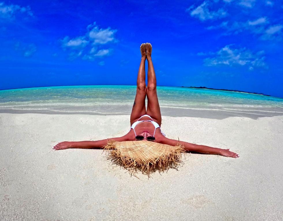 a person laying on the beach with their legs in the air at Adroit Beach Inn in Guraidhoo