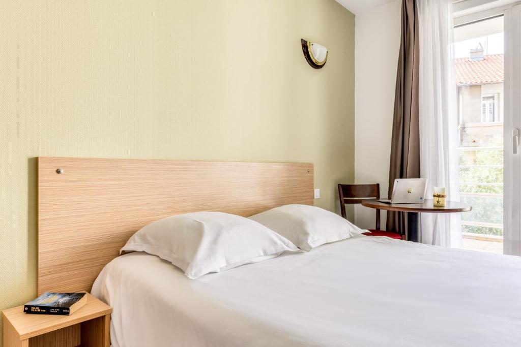 Un dormitorio con una cama blanca y una ventana. en Zenitude Hôtel-Résidences Béziers Centre, en Béziers