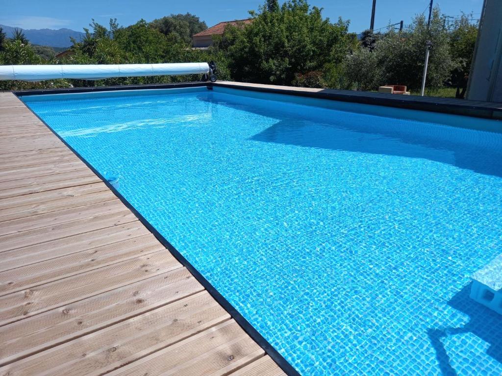 a swimming pool with a wooden deck and a blue pool at U SOLE in Ajaccio