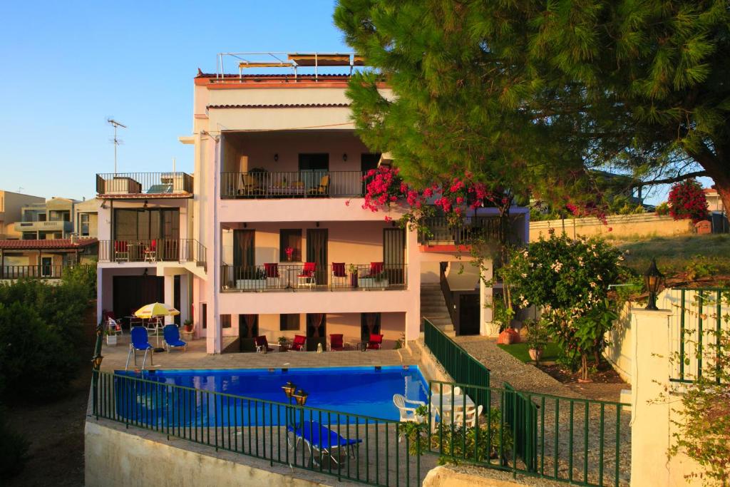 un edificio con piscina di fronte a una casa di Stroubis Studios I a Megás Limniónas