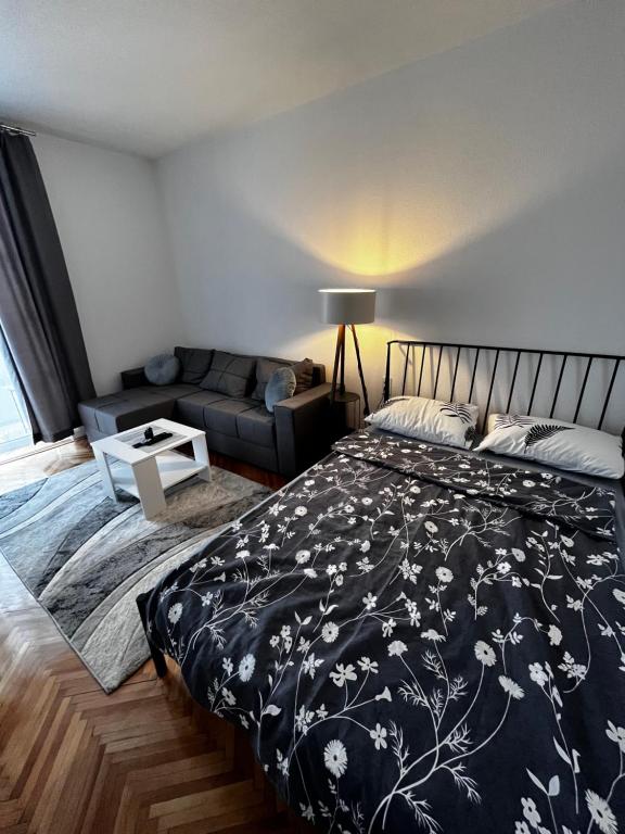 a bedroom with a bed and a couch at Apartman RISTIC in Vranje