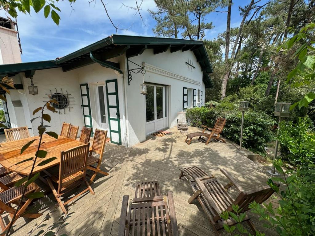un patio avec une table et des chaises en bois dans l'établissement CAPBRETON. Villa BAKENSACK avec terrasse pour 12 personnes wifi gratuit, à Capbreton