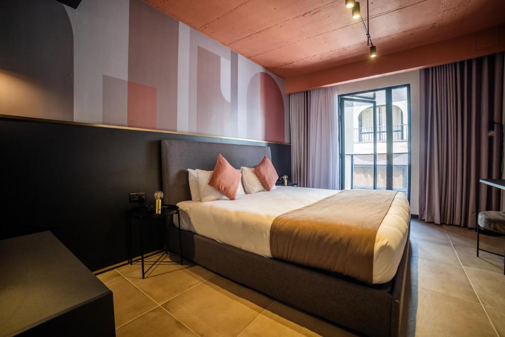 a bedroom with a bed and a large window at Eleven by Warren Collection in Sliema