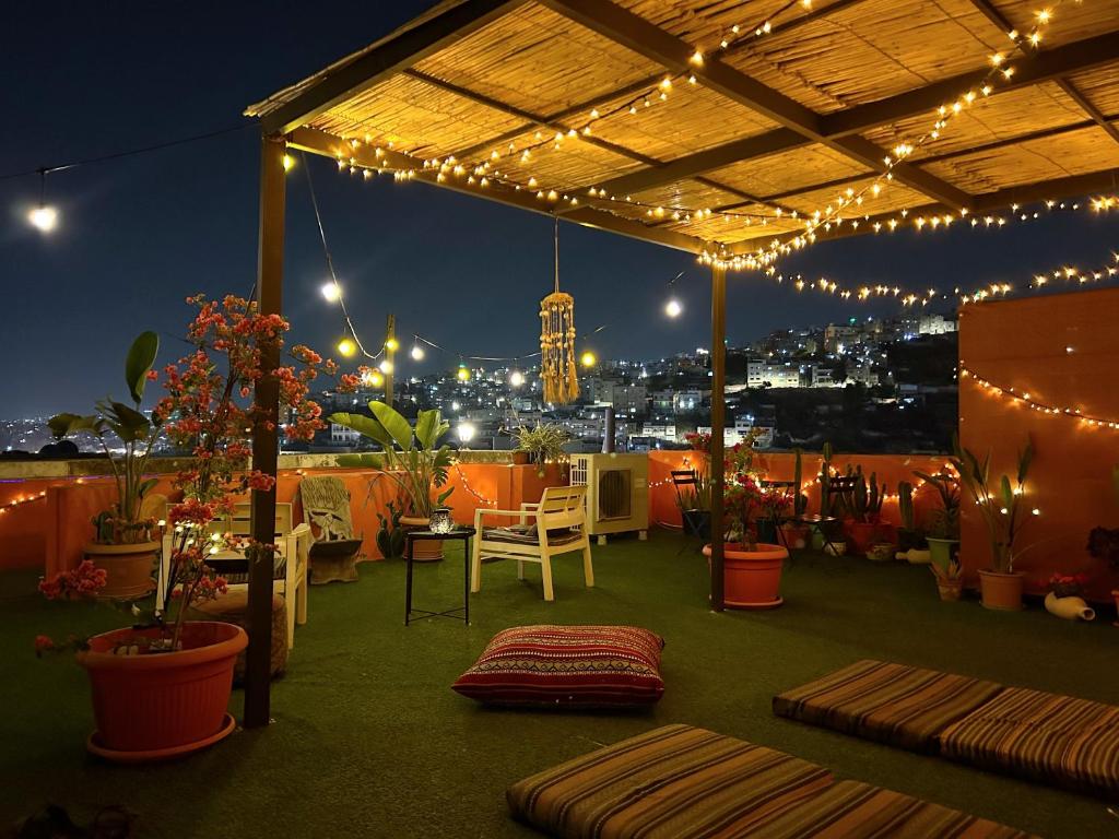 a rooftop patio with lights and tables and chairs at Medusa Home Stay in Amman