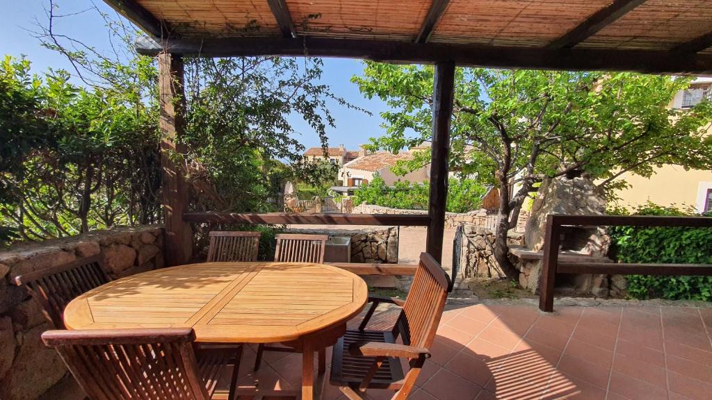 a wooden table and chairs on a patio at Porto Pollo, Il borgo villetta 3 camere da letto in Porto Pollo