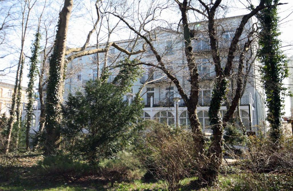 una gran casa blanca con árboles delante de ella en Warnemünde Appartement Parkblick REF 81886, en Warnemünde