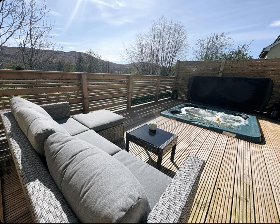 a couch sitting on a wooden deck with a television at Waternish Apartment in Corpach