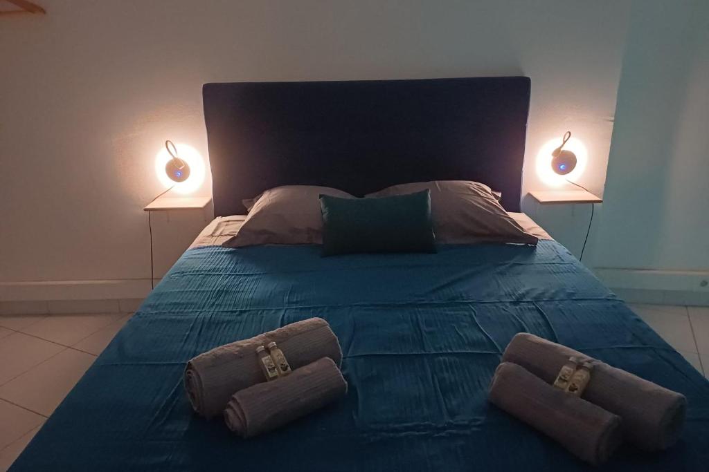 ein blaues Bett mit zwei Kissen und zwei Lampen darauf in der Unterkunft Room A340 in Papeete