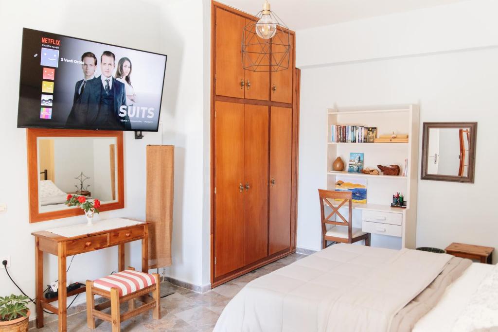 a bedroom with a bed and a tv on a wall at 3 Venti - Ostria in Liapades