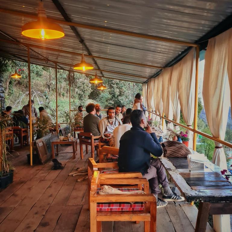 a group of people sitting at tables in a restaurant at EDM Hostel in Kangra