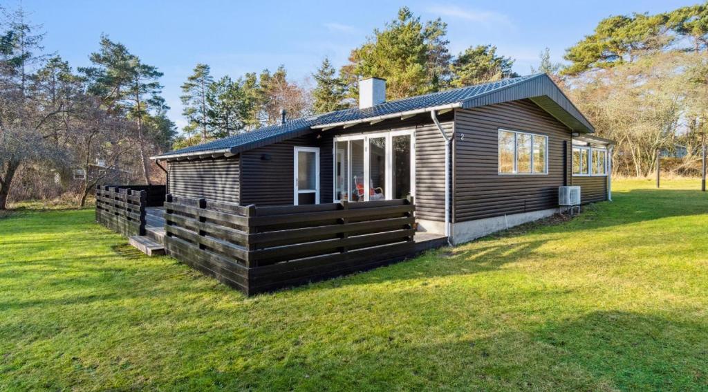una pequeña cabaña en un campo con césped en Lovely Summer House With Bornholm Atmosphere, en Vester Sømarken