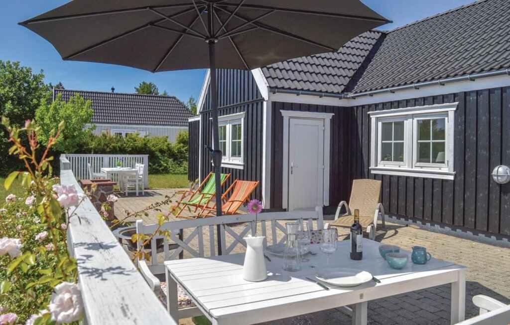 a picnic table with an umbrella in front of a tiny house at Modern Cottage Close To The Beach in Vejby