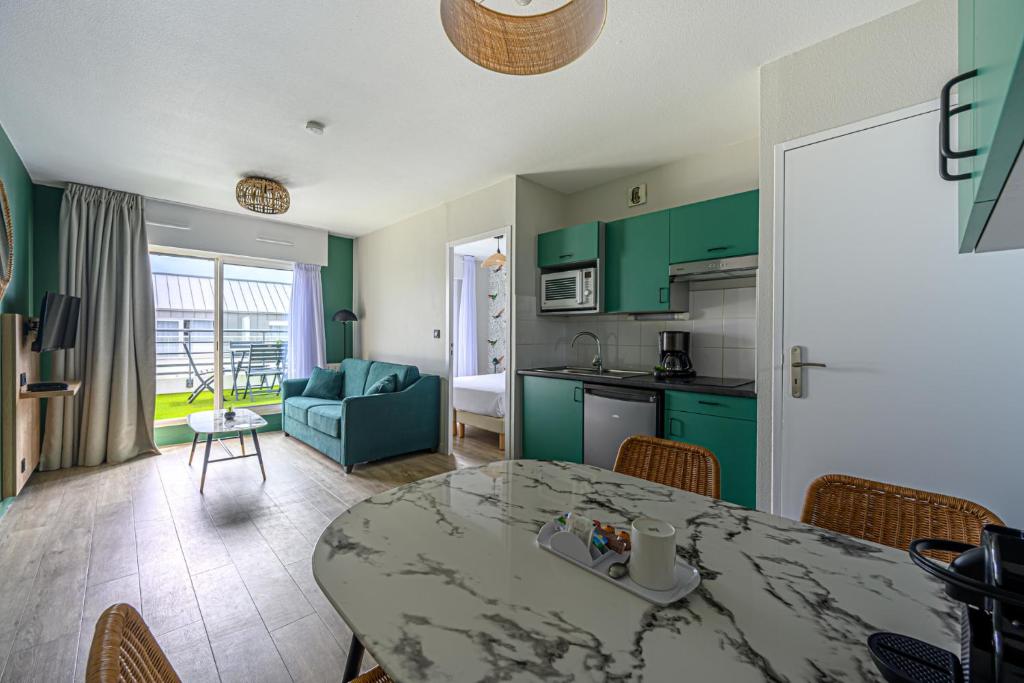 eine Küche und ein Wohnzimmer mit einem Tisch im Zimmer in der Unterkunft Appart Hôtel Le Liberté Vannes Centre-Ville in Vannes
