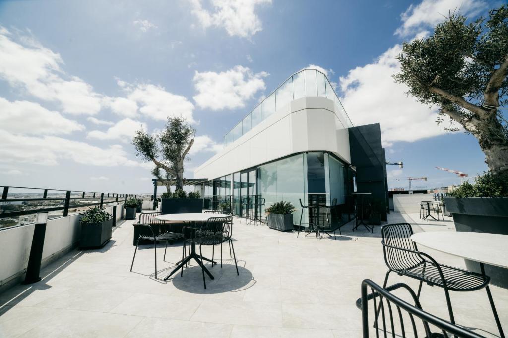 a patio with tables and chairs and a glass building at Park Heights by the Warren Collection in Msida