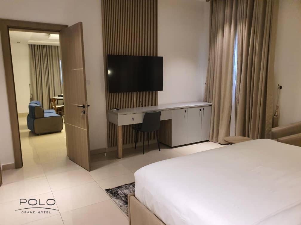 a hotel room with a bed and a desk with a television at Polo Grand Hotel in Maiduguri