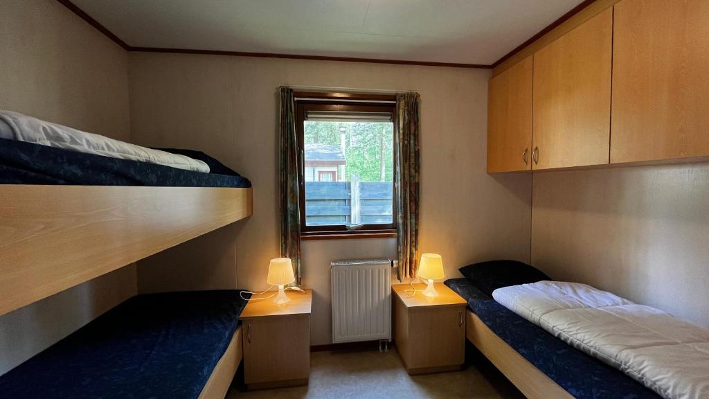 two bunk beds in a room with a window at Camping Boslust, Bungalow de Koekoek in Putten