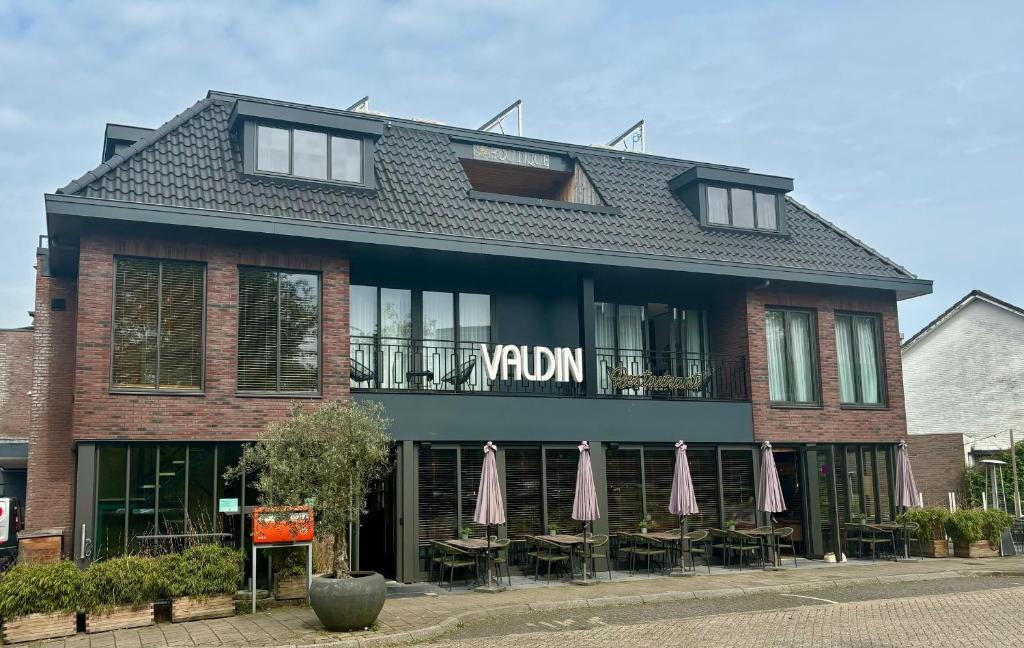 ein Gebäude mit Tischen und Sonnenschirmen davor in der Unterkunft Hotel La Boutique in Nijmegen
