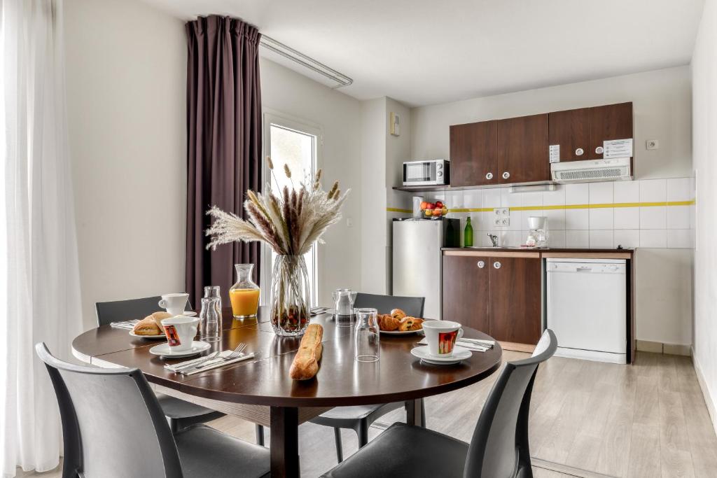 a kitchen and dining room with a table and chairs at Zenitude Hôtel-Résidences Béziers Centre in Béziers