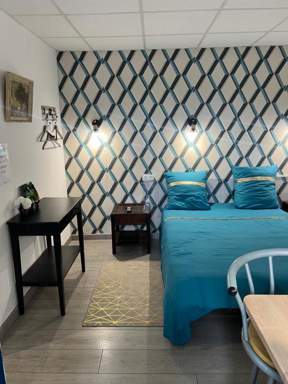 a bedroom with a blue bed and a table at Résidence Selva Appartements à Lourdes proche sanctuaire in Lourdes