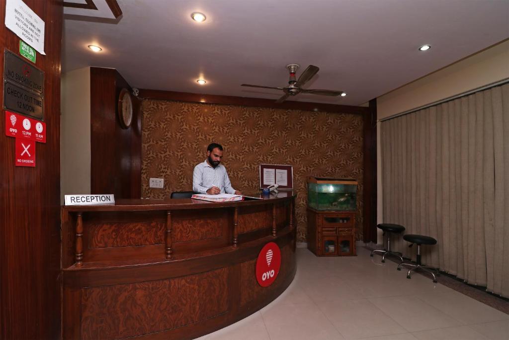 un hombre parado en un mostrador en el vestíbulo de un hotel en OYO Hotel Global Inn, en Nueva Delhi