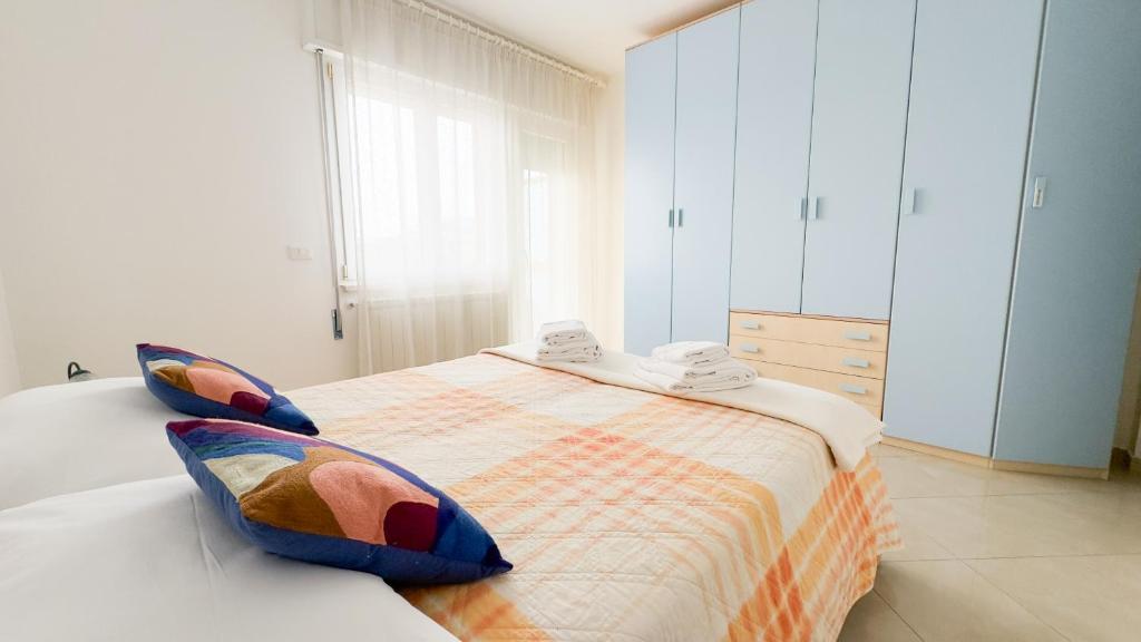 a white bedroom with a bed with a colorful blanket at Esperia Apartment by Ca-Sa Check in Chioggia
