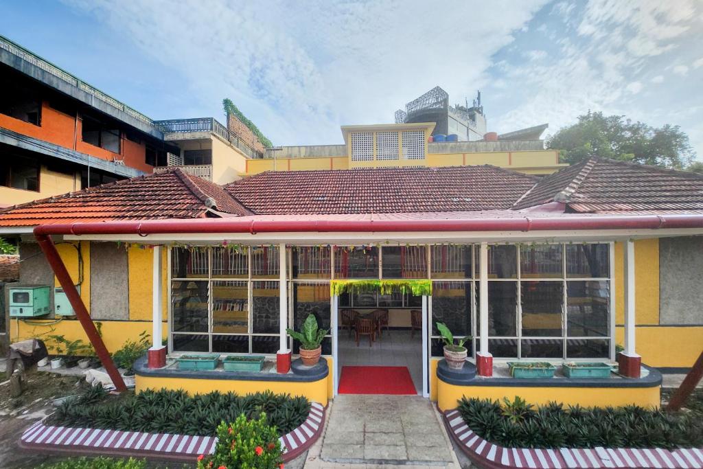 una casa amarilla con un porche con plantas. en RedDoorz Syariah Near Pelabuhan Sri Bintan Pura Tanjungpinang, en Tanjung Pinang