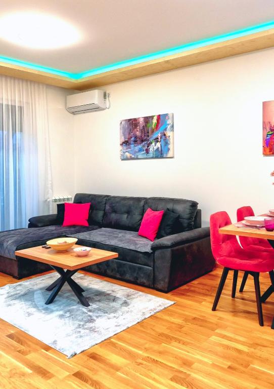 ein Wohnzimmer mit einem schwarzen Sofa und einem Tisch in der Unterkunft Royal Apartman in Čačak