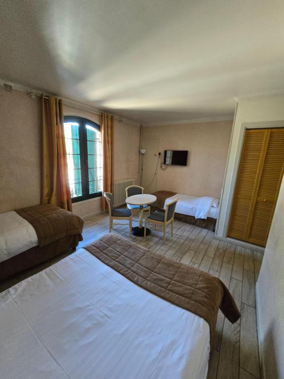 グラースにあるオーベルジュ レ アロームのベッド2台とテーブルが備わるホテルルームです。