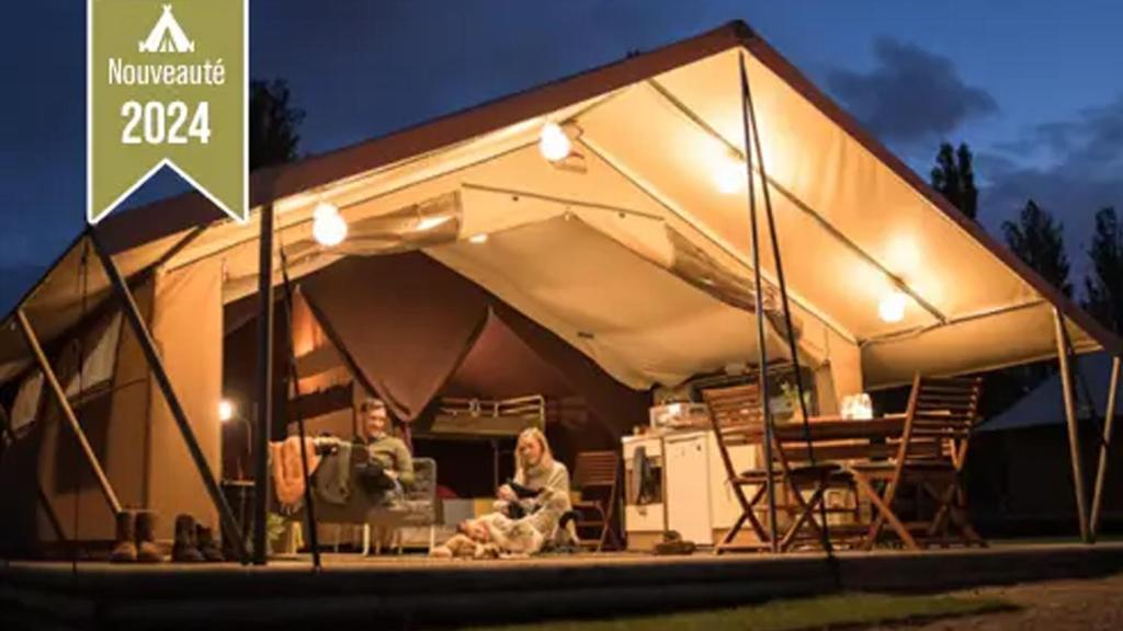 2 personnes assises dans une tente la nuit dans l'établissement Tente Lodge Safari - La Plage Autet, à Autet