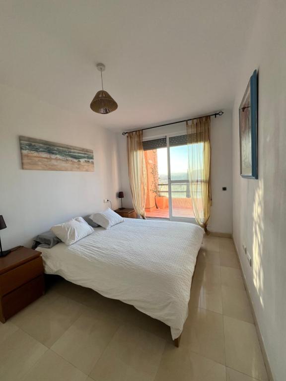 sypialnia z dużym łóżkiem i oknem w obiekcie Mojacar terrazas del Golf w mieście Mojácar