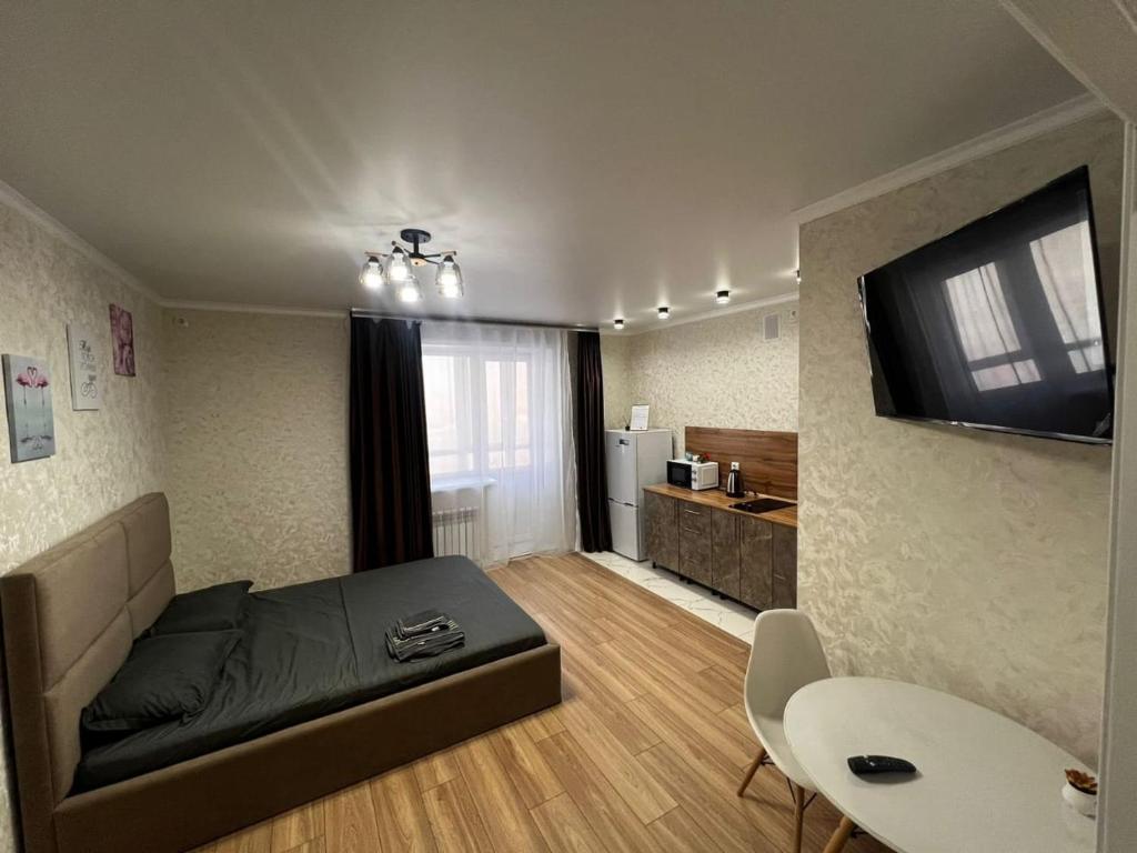 1 dormitorio con 1 cama y TV en la pared en Новая 1 комнатная квартира в мкр Аэропорт, en Kostanái