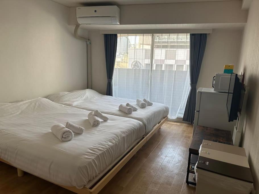 1 dormitorio con 1 cama con toallas enrolladas en Dynastshibuya涩谷一番館 en Tokio