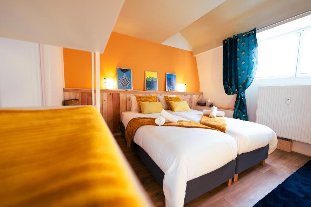 2 camas en una habitación con paredes de color naranja en Lets Relax - Coté Soleil Levant, en Mons