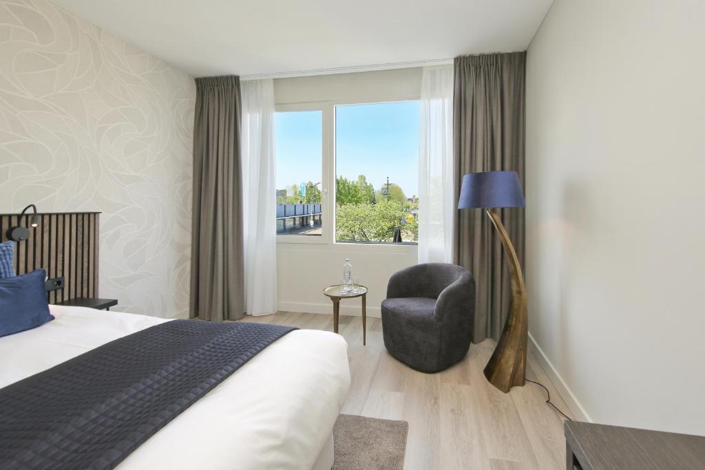 a bedroom with a bed and a chair and a window at Boutique Hotel Hans in Badhoevedorp
