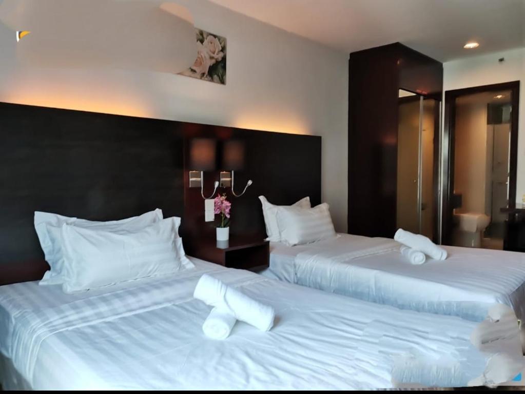 two beds in a hotel room with white sheets at Kk homeStay City suites Room Ming Garden Residence in Kota Kinabalu