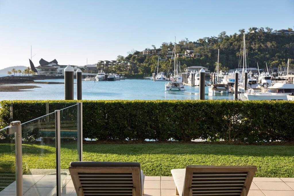 two chairs sitting on a patio overlooking a marina at Pavillions 17 Waterfront with Private Pool and Buggy in Hamilton Island