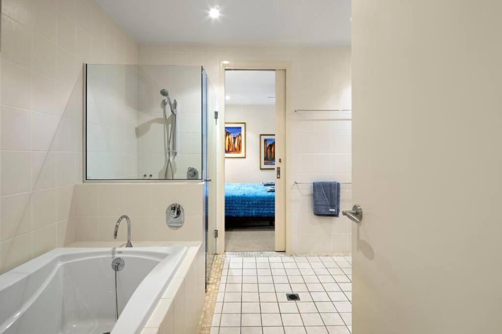 a white bathroom with a tub and a bedroom at Pavillions 17 Waterfront with Private Pool and Buggy in Hamilton Island