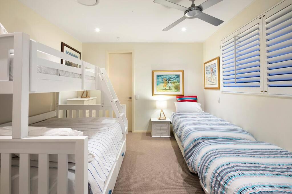 a bedroom with two bunk beds and a ceiling fan at Pavillions 17 Waterfront with Private Pool and Buggy in Hamilton Island