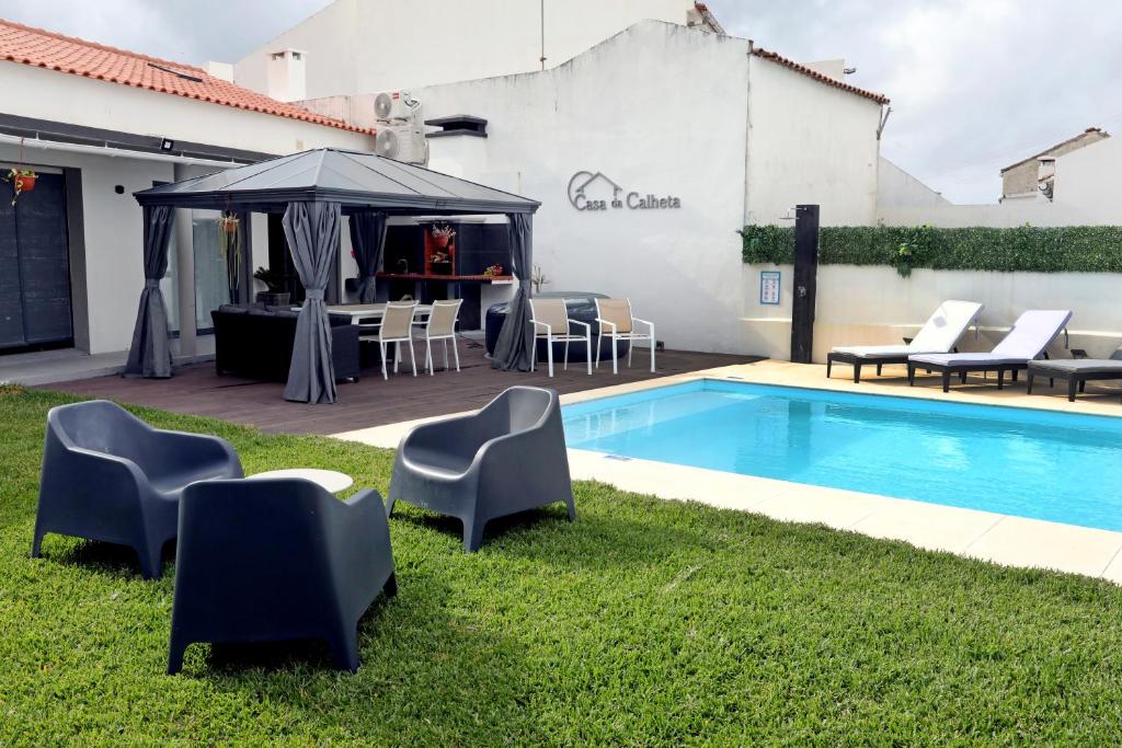 a pool with chairs and a table and an umbrella at Casa da Calheta in Maia