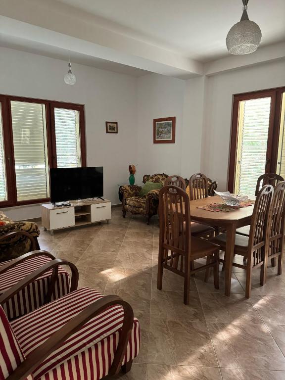 a living room with a table and chairs and a television at Apartament Gjiri i Lalëzit in Draç