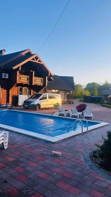 a swimming pool with chairs and a house at На ставку in Vyzhnytsya