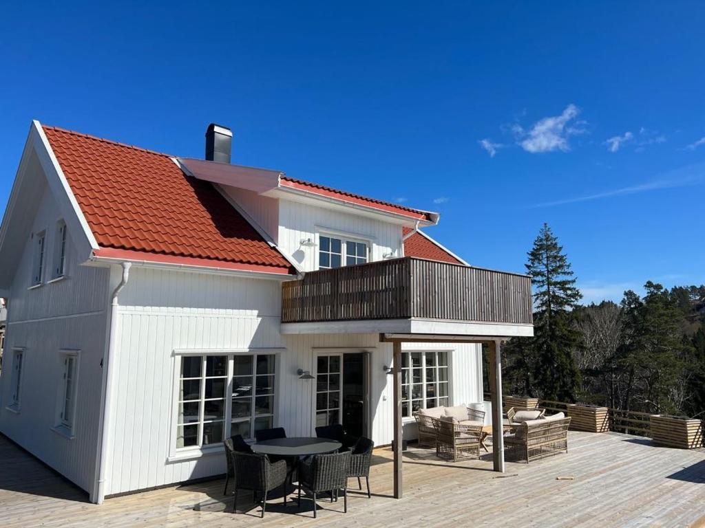 ein weißes Haus mit einer Terrasse und einem Tisch in der Unterkunft Hytteperle in Risør