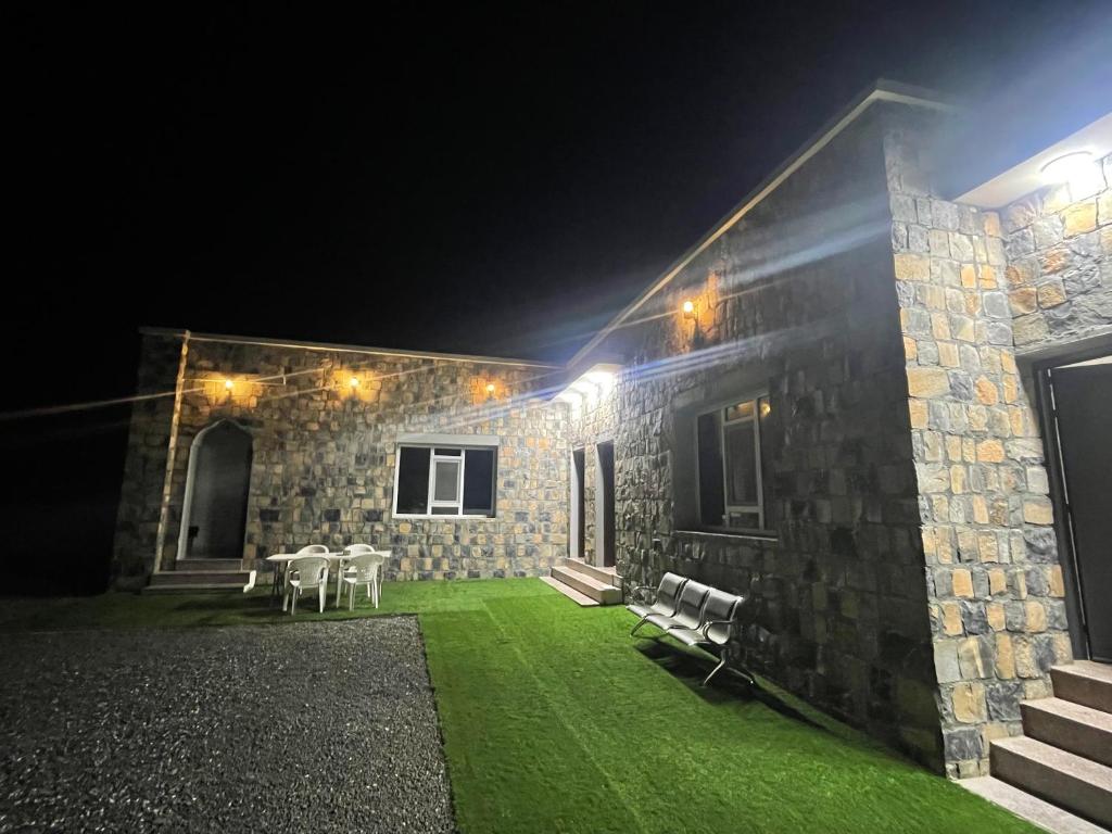 una casa de piedra con un patio verde por la noche en Jabal Shams, the summit house en Misfāh