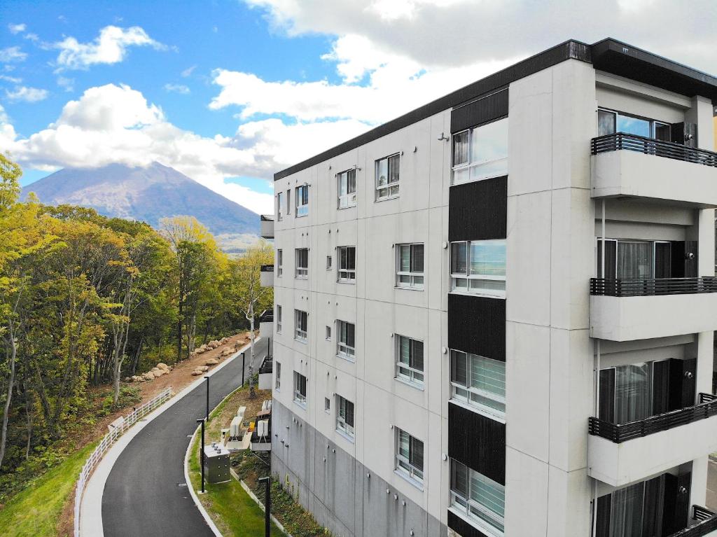 um edifício de apartamentos com uma montanha ao fundo em The Freshwater em Niseko