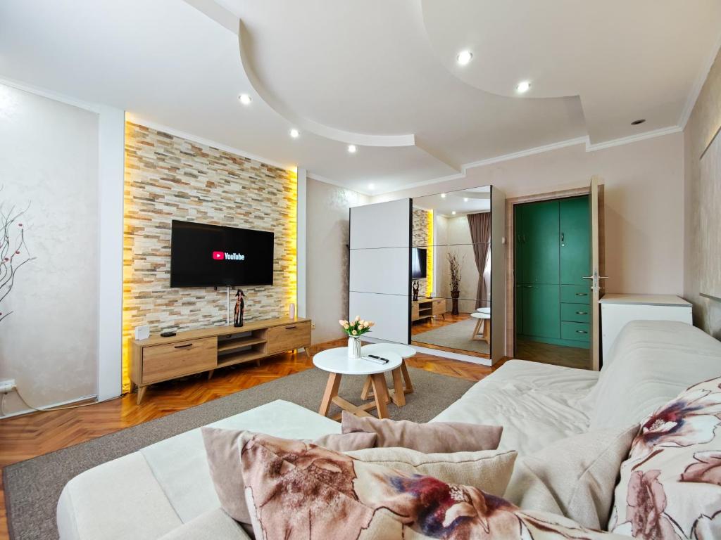 a living room with a couch and a tv on a brick wall at Apartman Julija in Donji Milanovac