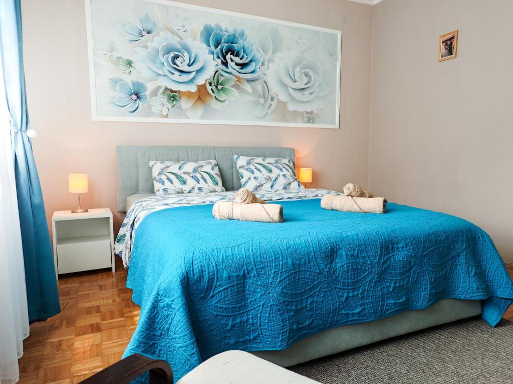 a bedroom with a blue bed with a painting on the wall at Apartman Julija in Donji Milanovac