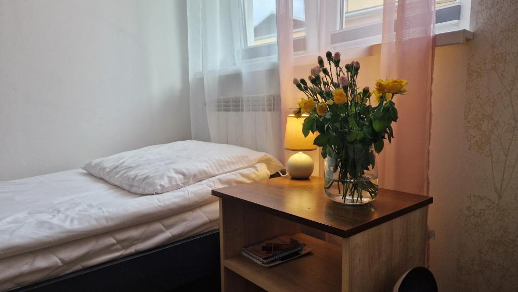 a bedroom with a vase of flowers on a table at Apartament w centrum Piwnicznej in Piwniczna-Zdrój
