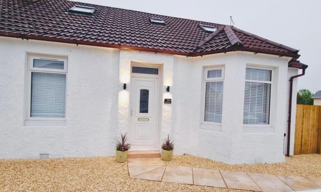 uma casa de tijolos brancos com uma porta branca em Harling House em Prestwick